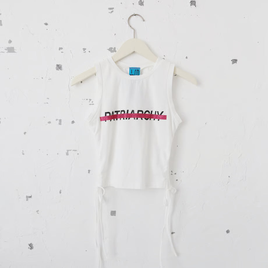ホワイトの丈短めのTシャツにPatriarchyの文字とそれを打ち消すようにピンクのラメのキラキラでプリントされている。