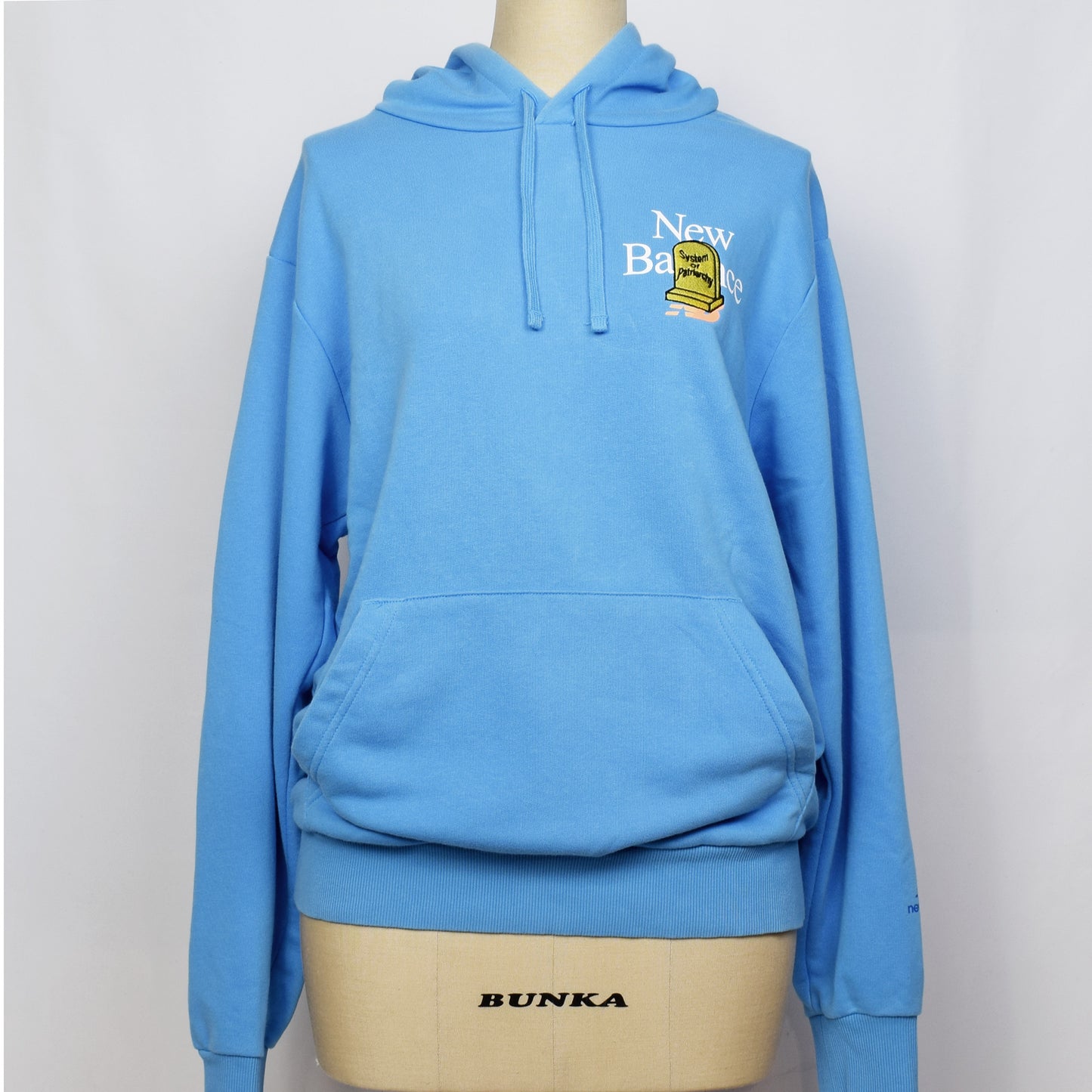 ライトブルーのプルオーバーのパーカーの胸に黄色の家父長制のお墓の刺繍。