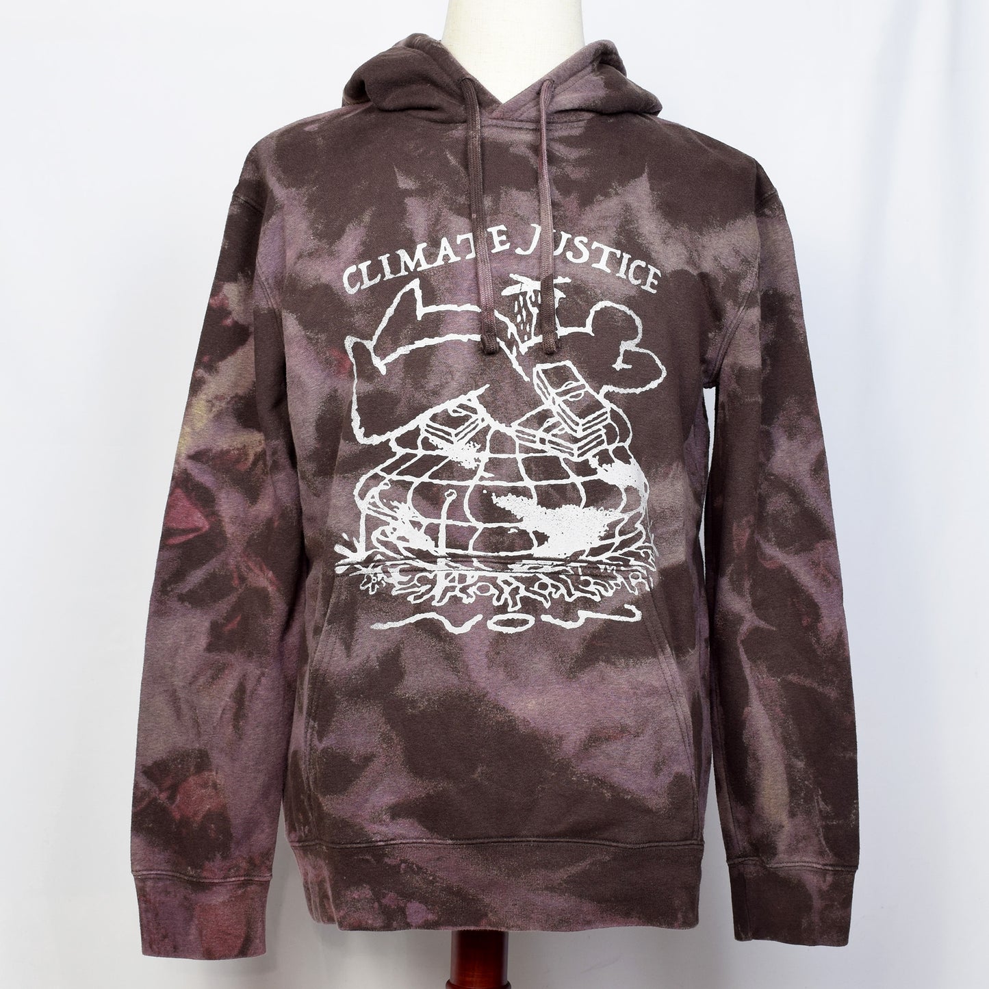 ブラウンのタイダイ柄プルオーバーパーカーにClimate Justiceと戦闘機を持った一人の大きい人間と札束が大勢の人と地球を押し潰しているイラストがプリントされている。