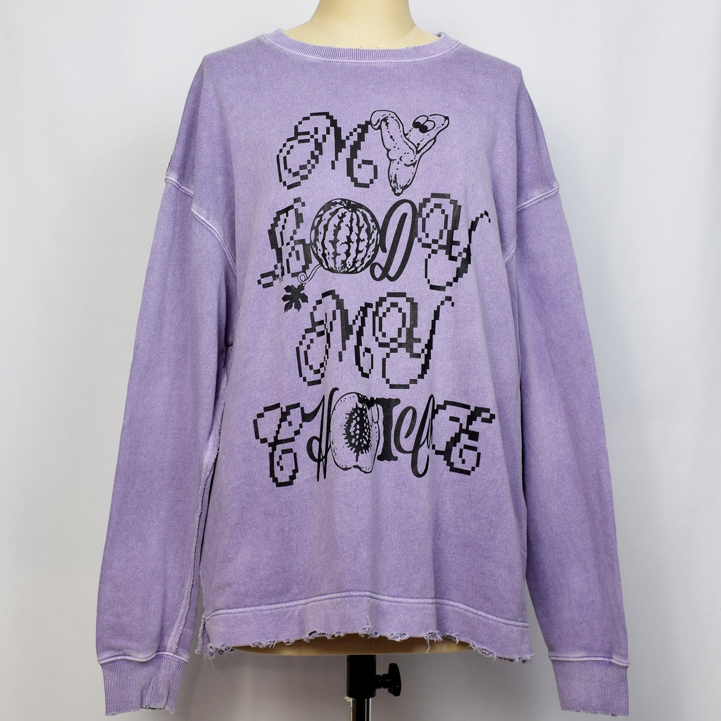 ラベンダー色の長袖トップスにMY BODY MY CHOICEとバナナ、プラム、スイカのイラストのプリント。袖、襟口にダメージ加工