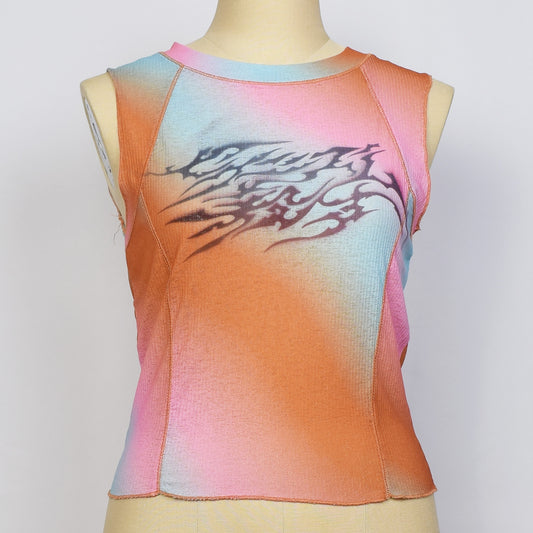 オレンジ、ピンク、ブルーのグラデーションの袖なしのタイトトップスにセクシズム殺すと書かれたメタルロゴ風のプリント。