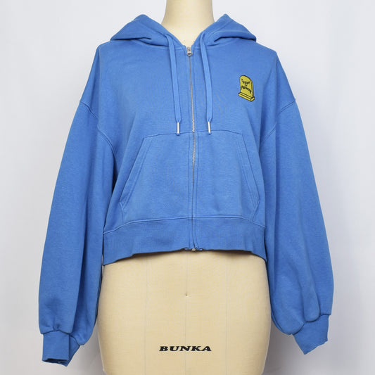 ライトブルーのクロップド前開きパーカーの胸に黄色の家父長制のお墓の刺繍。