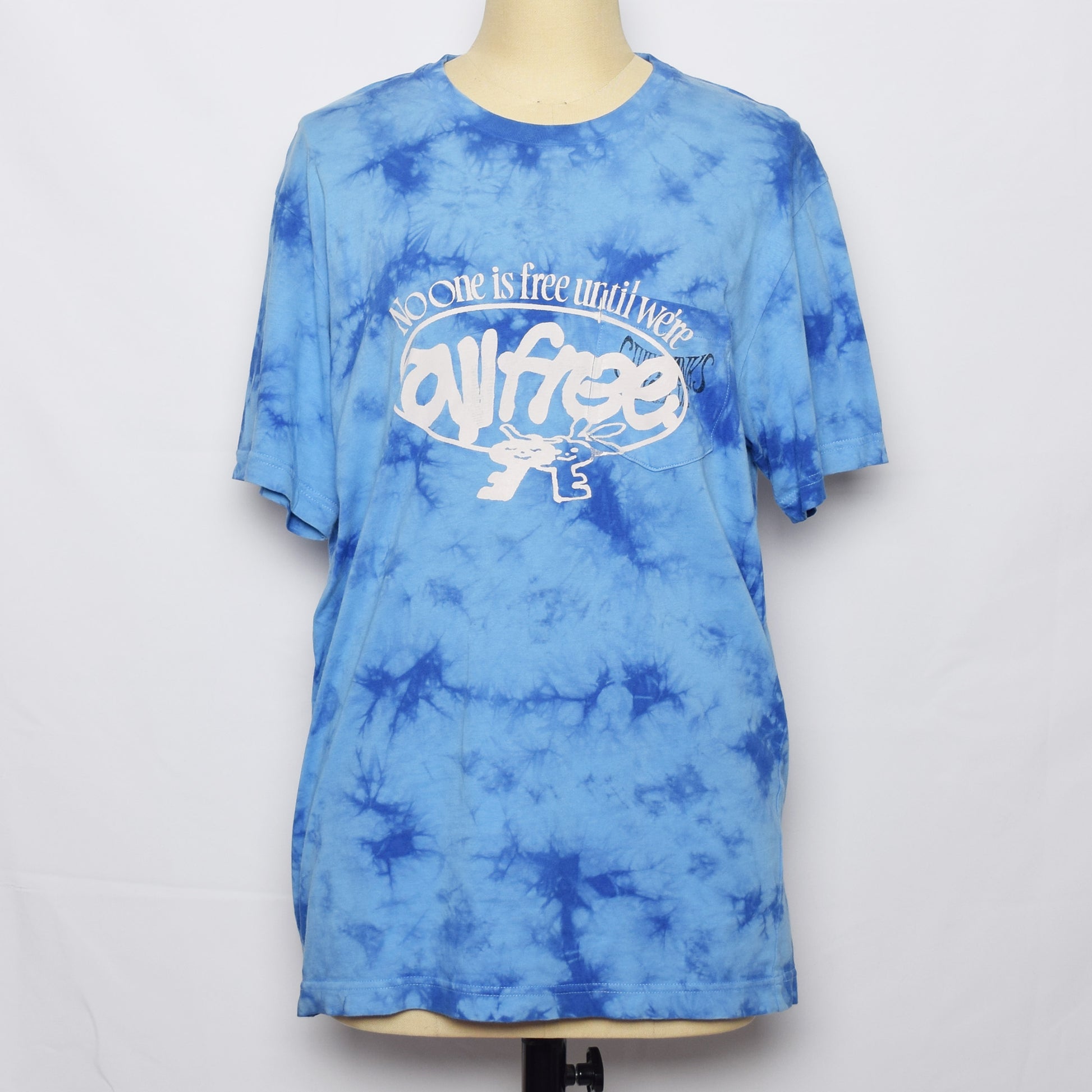 ライトブルーのタイダイ染めのTシャツにNo one is free until we are all freeの文字と鍵のキャラクターがプリントされている