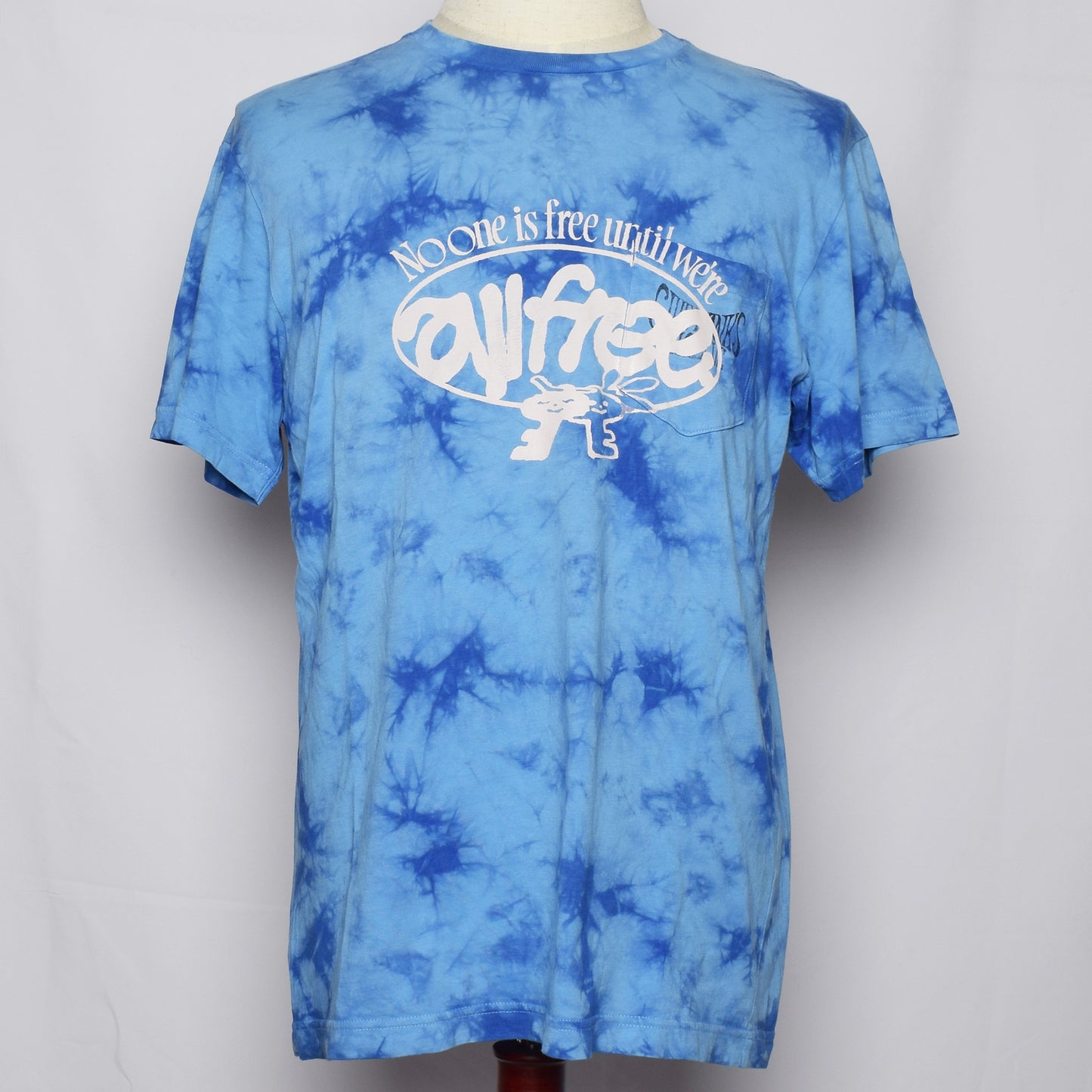 ライトブルーのタイダイ染めのTシャツにNo one is free until we are all freeの文字と鍵のキャラクターがプリントされている