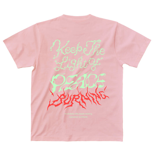 淡いピンクのボディのTシャツの背面。背中には、Keep The Light of PEACE BURNING、その下にIn solidarity with people resisting oppression worldwideの文字がプリントされている。
"Keep The Light of"の文字は淡いイエローグリーンでキラキラしたトゥインクルがあしらわれ、"PEACE"は風で揺らぐ中でか細く灯されている火のようなイメージ、その下の"BURNING"はレッドで燃え盛る炎のようなイメージ。

