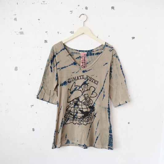 ベージュとネイビーのタイダイ柄Vネック半袖TシャツにCLIMATE JUSTICEの文字と一人の大きな人間と札束に地球と多くの人が押し潰されているグラフィック。