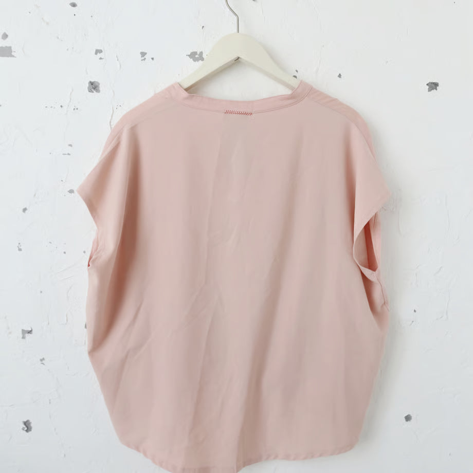 ピンク色のVネックのシャツカットソーに選択の権利とメタルロゴ風に書かれたプリントとキラキラしたグラフィックのプリントがされている。