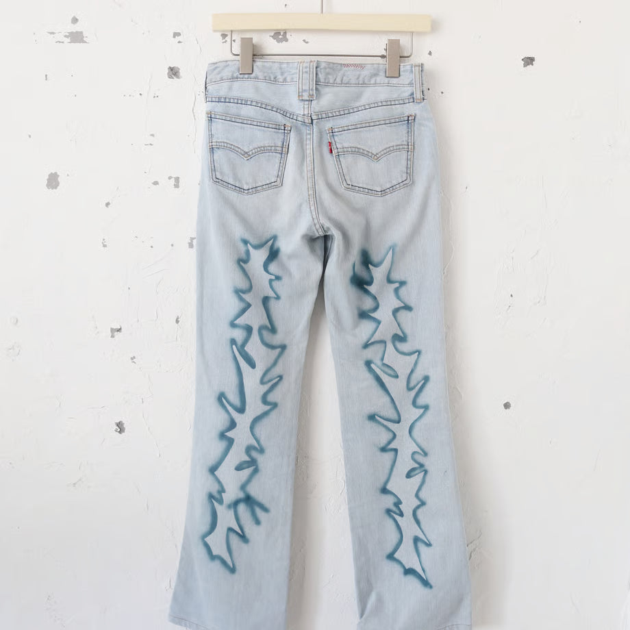 薄い色のデニムパンツに稲妻のようなスプレーペイントと、黒いプリントでno fasism no racism no sexism no colonialism no war　とプリントされている。