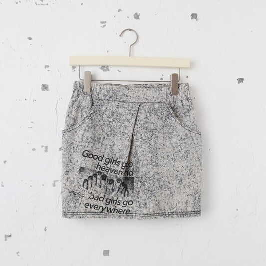 デニム素材のミニスカートにgood girls go to heaven  bad girls go everywhere.の文字と、ペディキュアが塗られた足の写真のグラフィックがプリントされている。