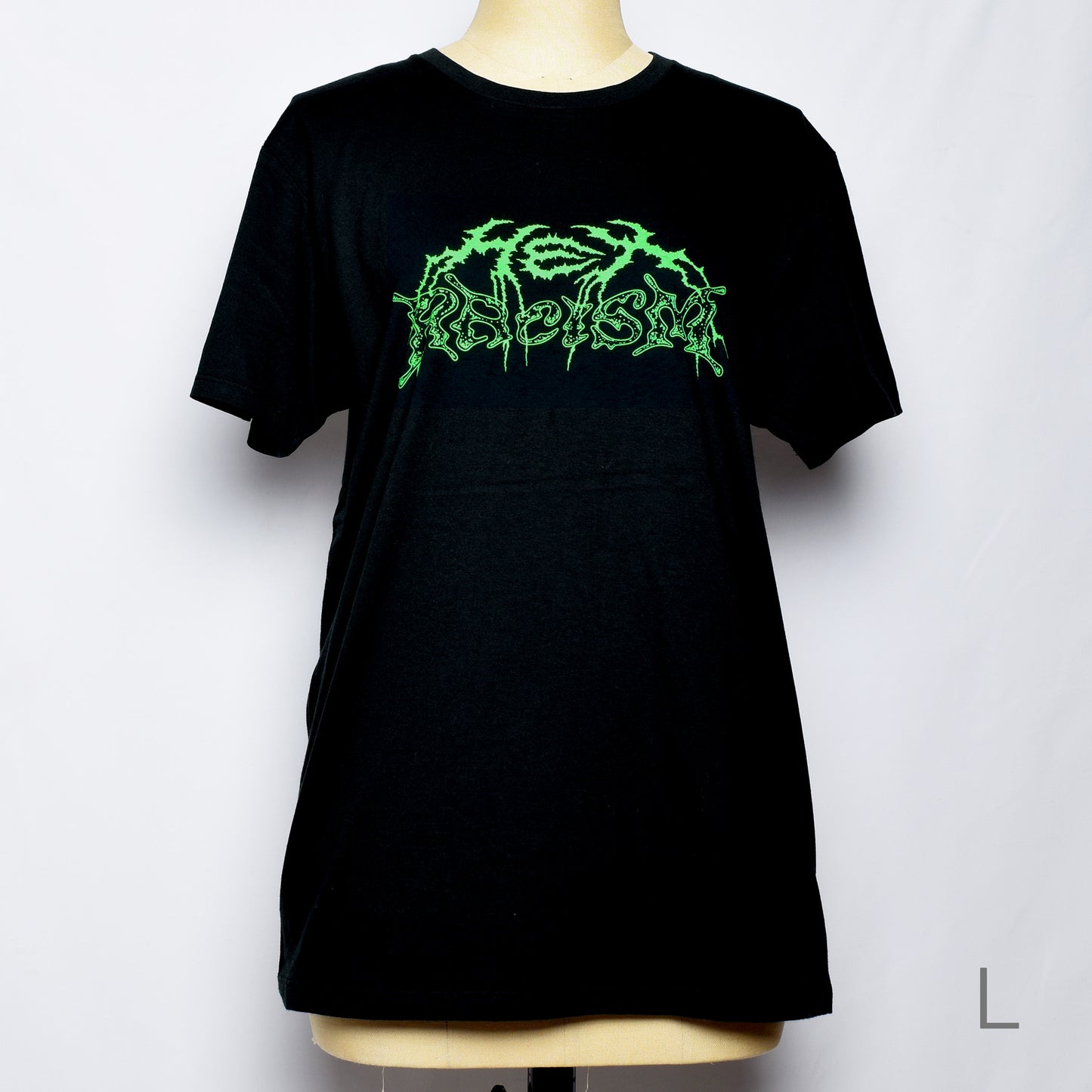 黒のTシャツにメタル風ロゴでHEX RACISM と蛍光グリーンでプリントされている。後ろは祝共生の文字と悪魔、魔女、髭の長い男性の魔女が笑顔でダンスしているイラストがグレーでプリントされている。