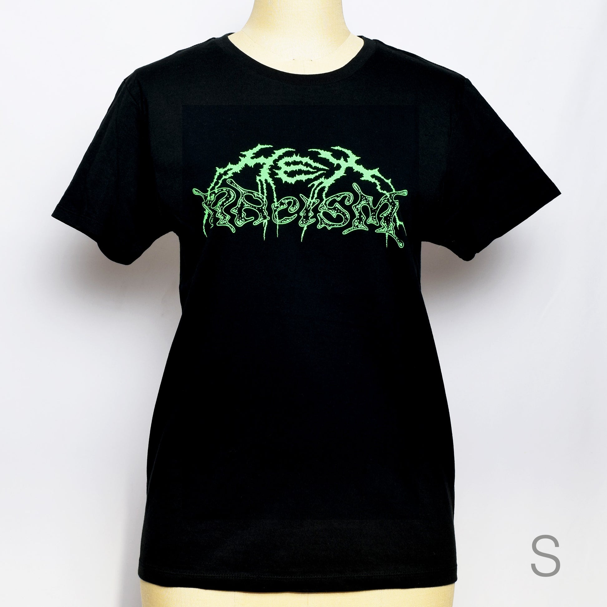 黒のTシャツにメタル風ロゴでHEX RACISM と蛍光グリーンでプリントされている。後ろは祝共生の文字と悪魔、魔女、髭の長い男性の魔女が笑顔でダンスしているイラストがグレーでプリントされている。