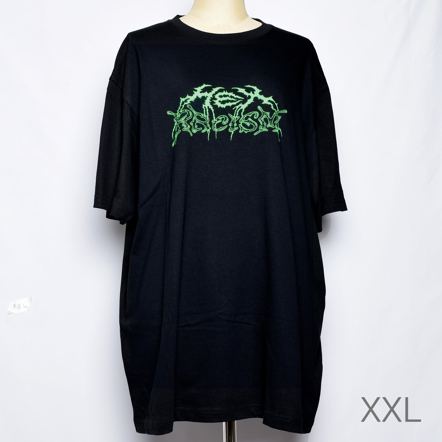 黒のTシャツにメタル風ロゴでHEX RACISM と蛍光グリーンでプリントされている。後ろは祝共生の文字と悪魔、魔女、髭の長い男性の魔女が笑顔でダンスしているイラストがグレーでプリントされている。