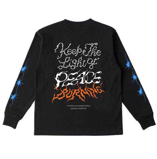 ブラックのボディのロングスリーブTシャツの背面。背中には、Keep The Light of PEACE BURNING、その下にIn solidarity with people resisting oppression worldwideの文字がプリントされている。
"Keep The Light of"の文字は白色でキラキラしたトゥインクルがあしらわれ、"PEACE"は風で揺らぐ中でか細く灯されている火のようなイメージ、その下の"BURNING"はブルーで燃え盛る炎のようなイメージ。
また袖には、発光するペンライトの光が3つ連なるブルーのプリンとかある。