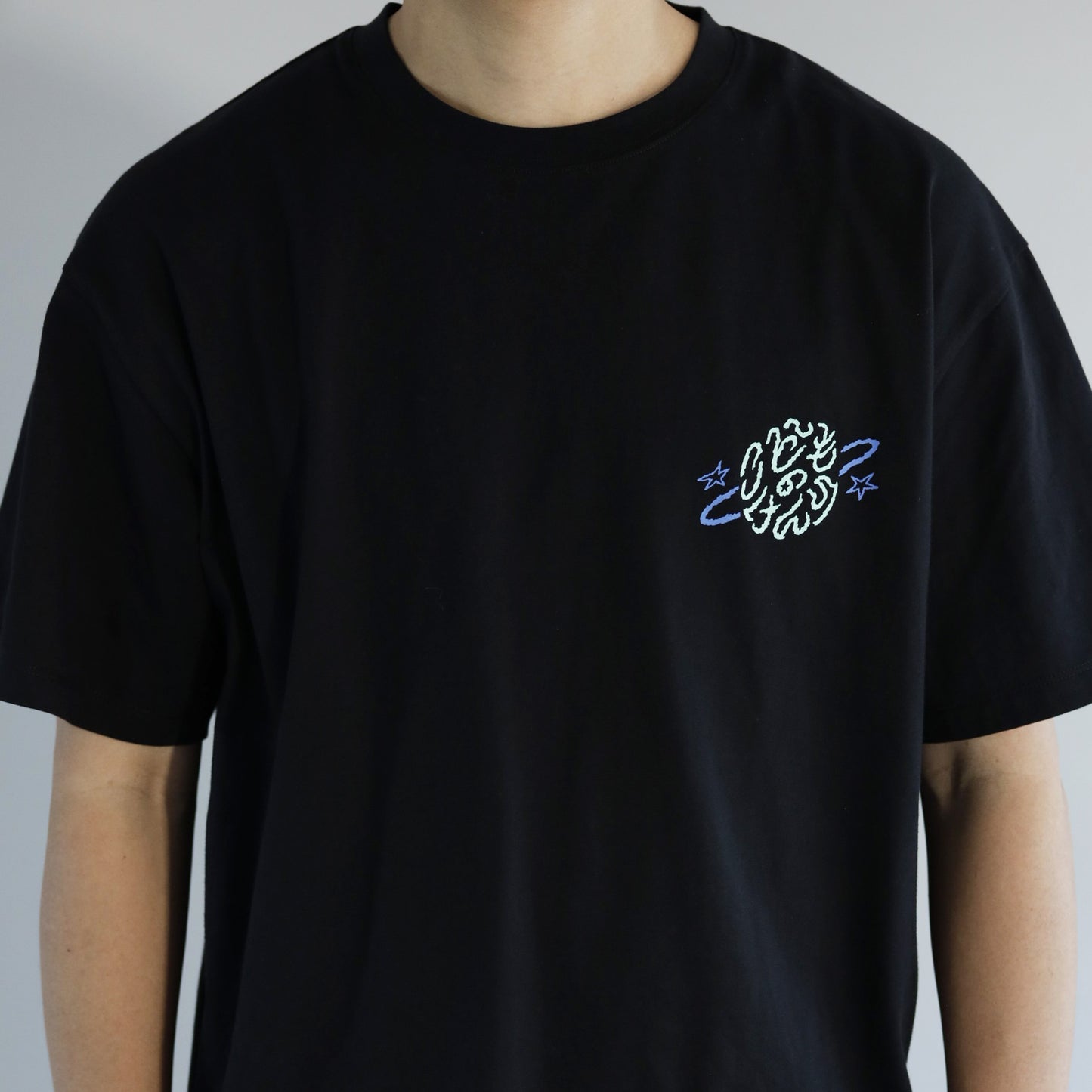 黒いTシャツの左胸ミントグリーンとブルーの「こどものけんり」の文字のプリントがある