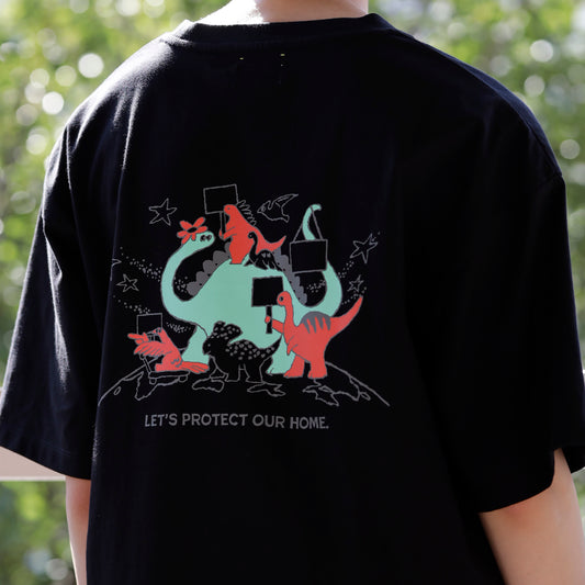 黒いTシャツのバックプリントとして、様々な種類の恐竜たちがプラカードを持って行進しているレッドとミントグリーンのイラストがあり、その下に、「LET'S PROTECT OUR HOME.」の文字がある。