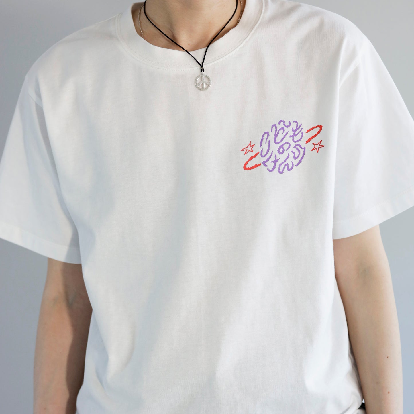 白いTシャツの左胸パープルとレッドの「こどものけんり」の文字のプリントがある